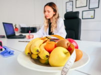 a woman sitting at a desk with a bowl of fruit